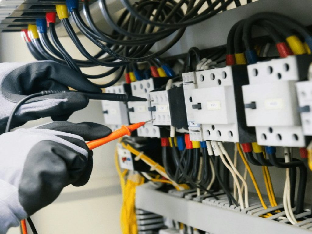 electricista revisando un cuadro eléctrico para registrar horas, kilómetros y materiales en el parte de trabajo
